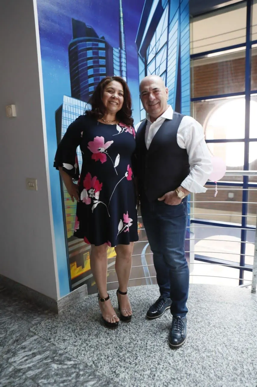 Mario e Mercedes insieme davanti a una parete blu