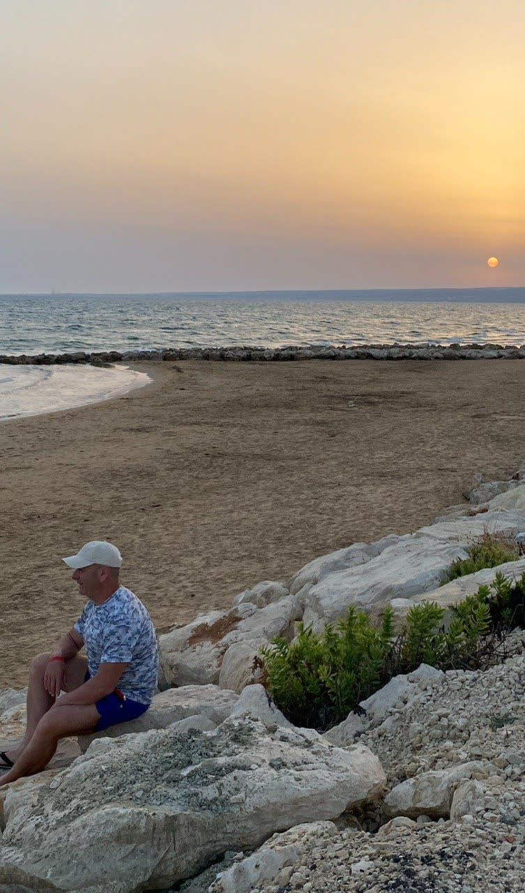 Mario seduto sugli scogli al tramonto