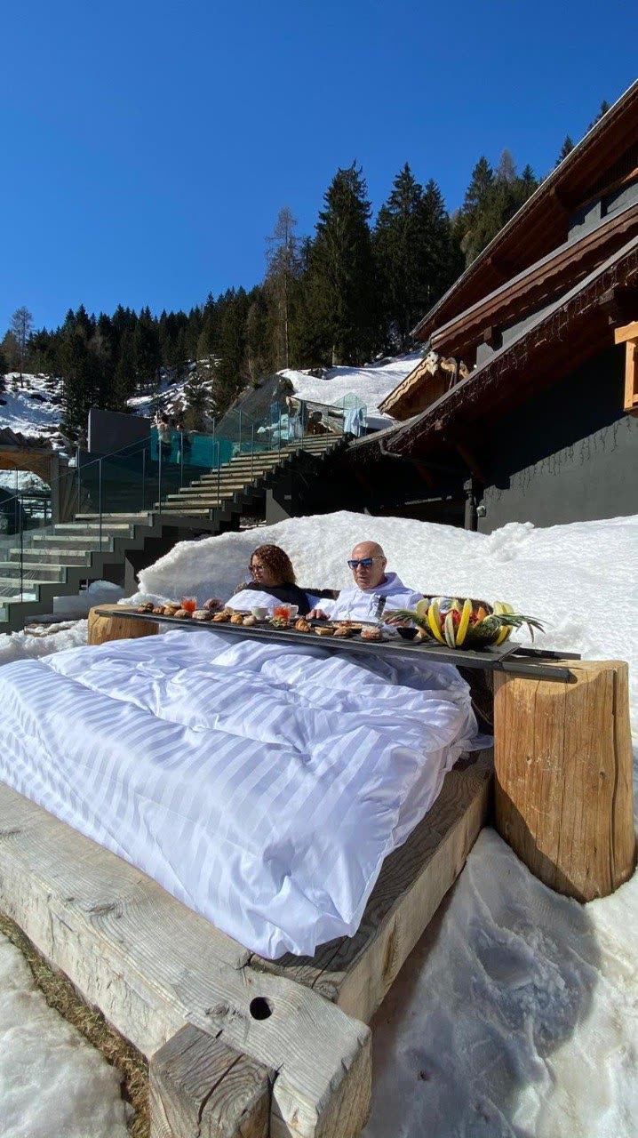 Mario e Mercedes fanno colazione all'aperto nella neve davanti a uno chalet